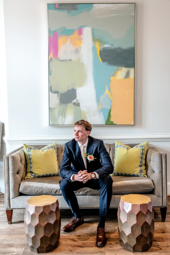 A groom sits on a sofa in a colorful living room space