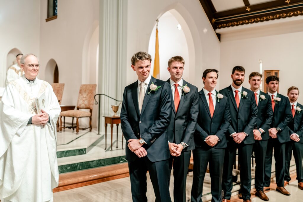 A groom smiles as he watches his bride walk down the aisle