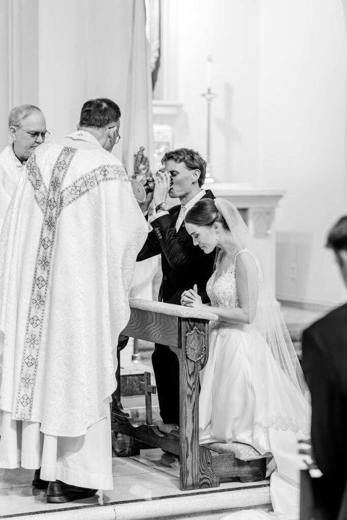 A groom receives communion during his wedding