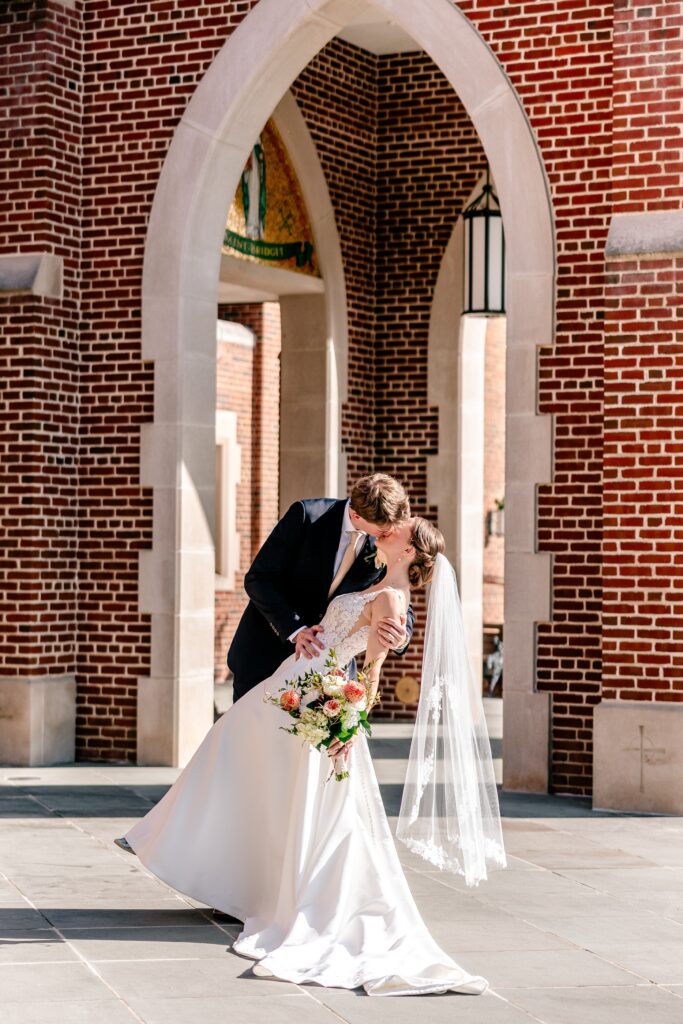 A bride and groom share a kiss outside the church during their The Estate at Independence wedding day