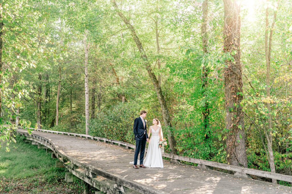 A bride and groom walk together across a bridge during their The Estate at Independence wedding