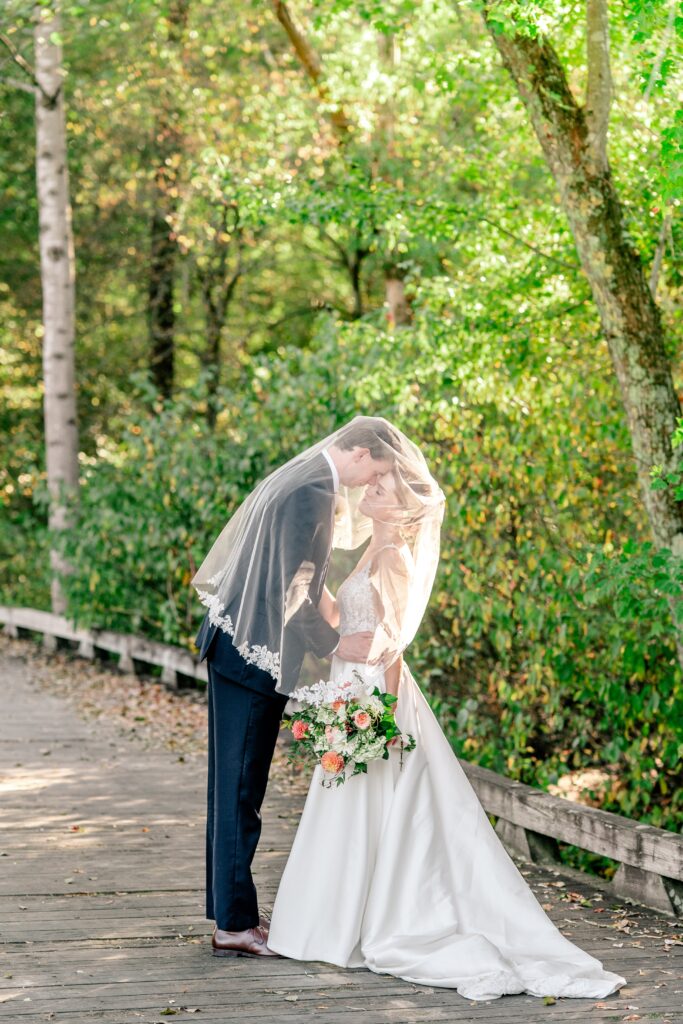 A bride and groom posed under her veil by Richmond wedding photographer Beauty of the Soul Studio