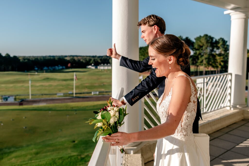 A bride and groom cheer from a balcony during their The Estate at Independence wedding