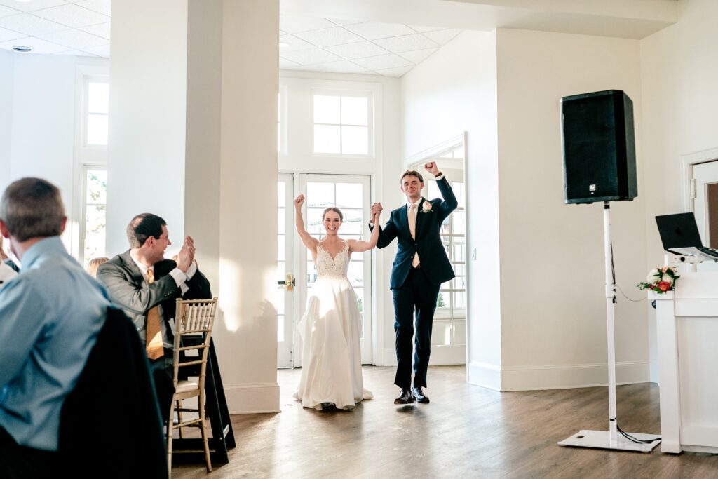 A bride and groom cheering as they enter their wedding reception toward the Catholic wedding photographer