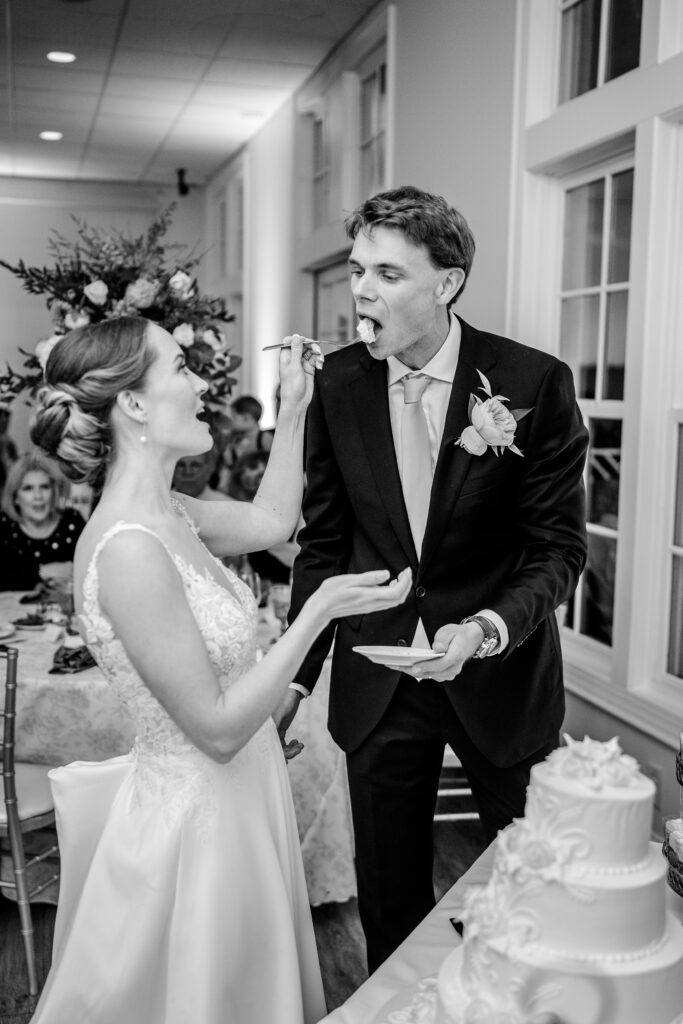A bride feeds her groom cake in front of their Richmond wedding photographer