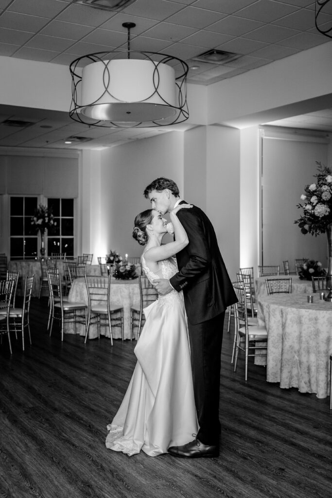 A groom kisses his bride on the forehead during their private last dance