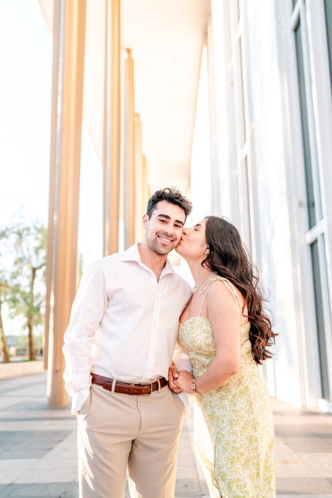 A woman kissing her fiancé on the cheek during their Kennedy Center engagement photos