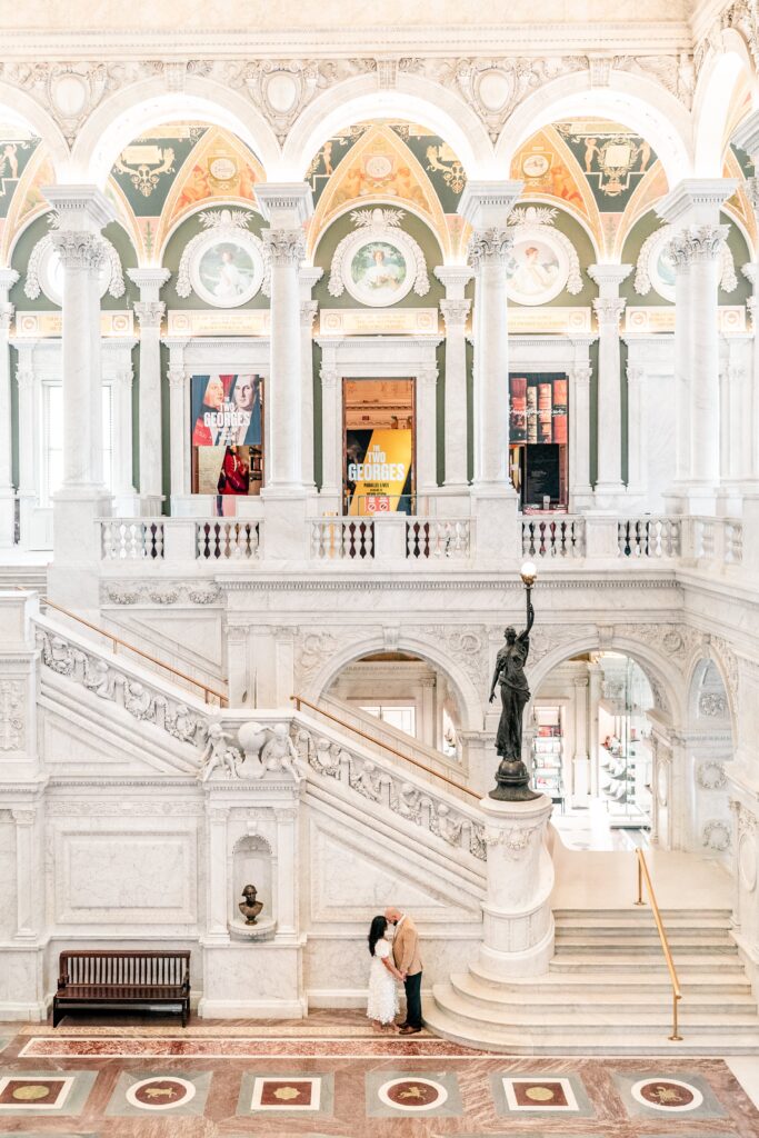 A couple posed at the bottom of the marble staircase for their Library of Congress engagement photos