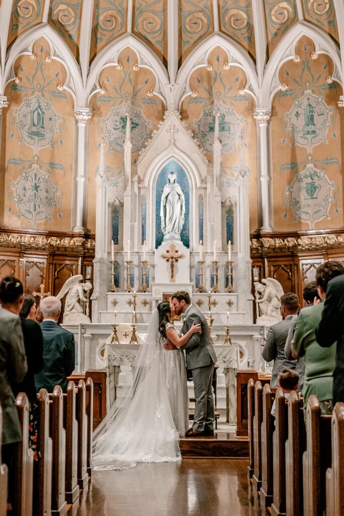 A bride and groom kiss at the end of their Catholic ceremony with their Washington DC wedding photographer