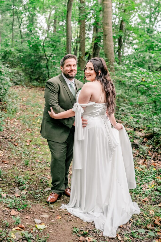 A bride and groom posing for portraits in the woods for their Stone Manor Boutique Inn wedding