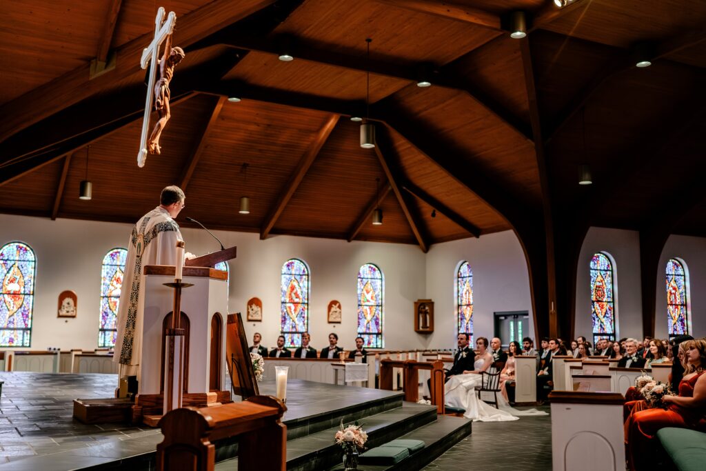 A priest gives a homily to a crowded church before a Gable Five wedding reception
