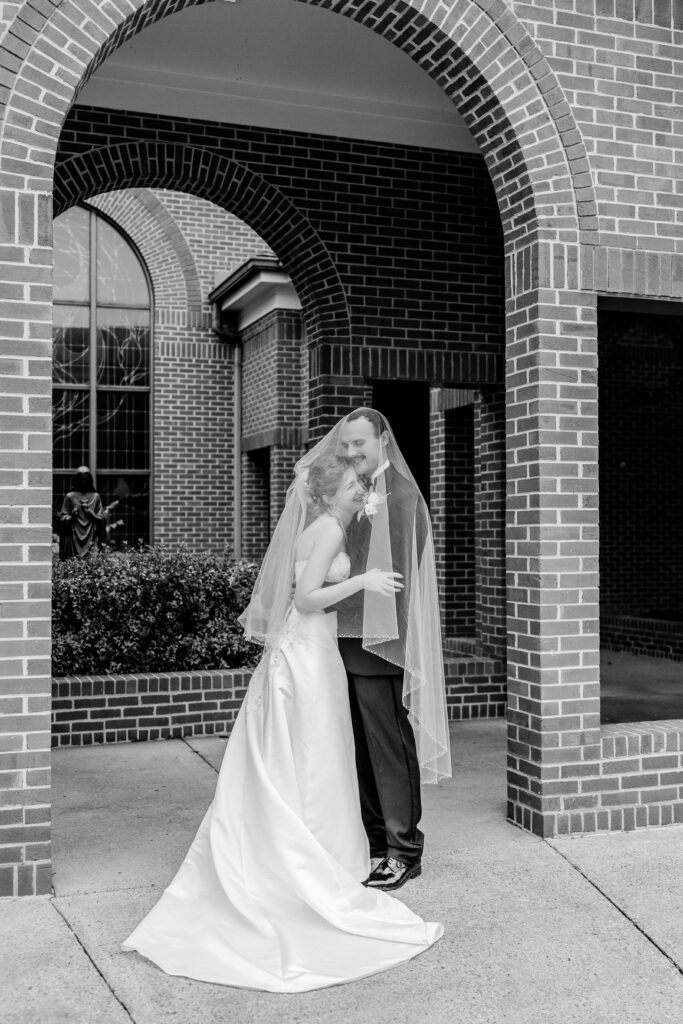 A bride and groom laugh together under the blusher