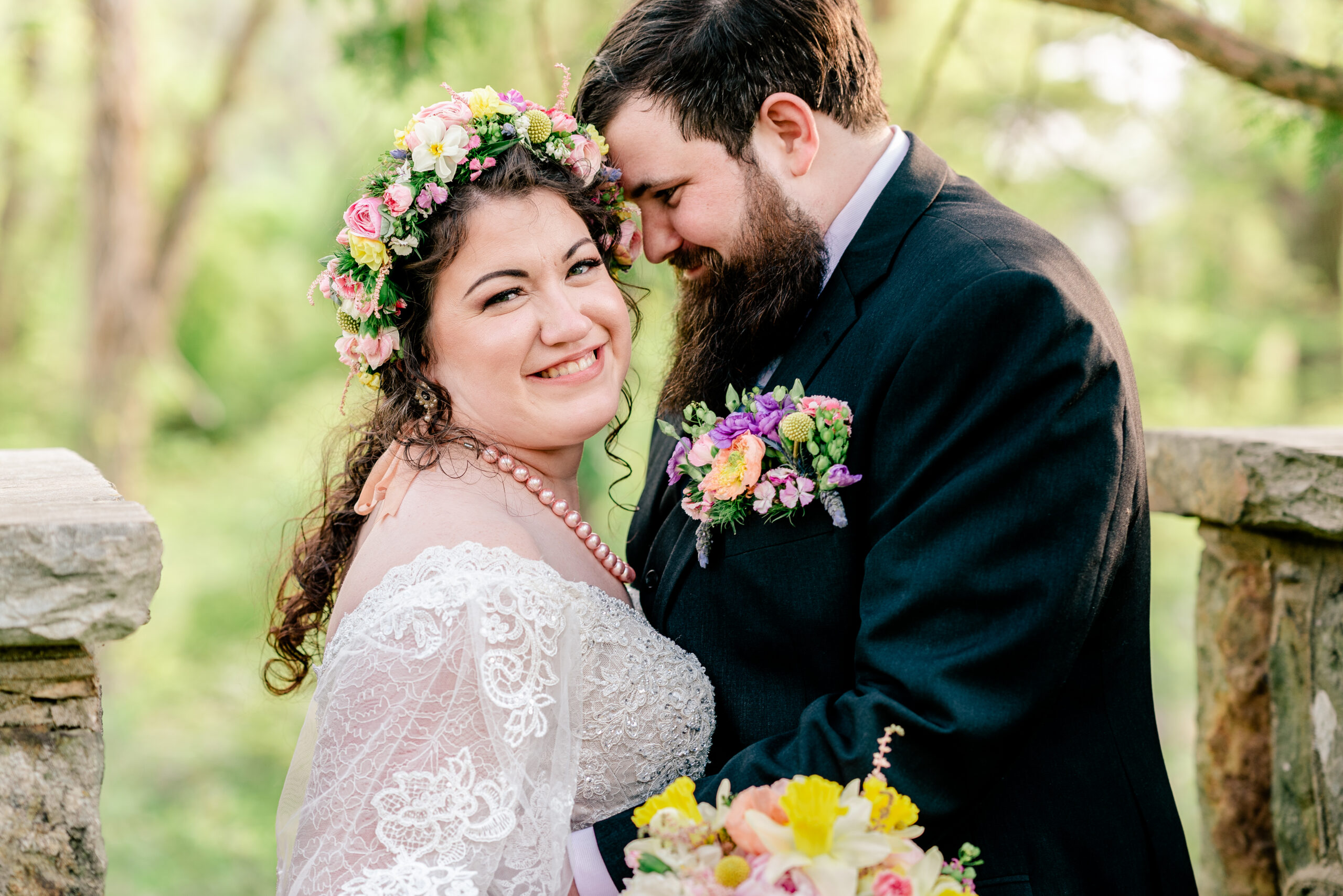 A bride smiling at the camera as her groom nuzzles her temple during their Rust Manor House wedding in Leesburg VA