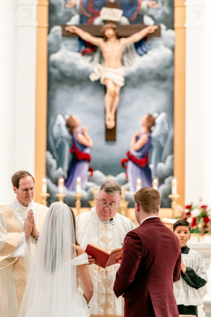 A bride and groom standing before the priest at St. Francis de Sales