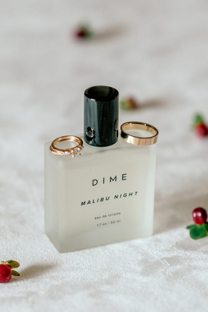 A Dime Malibu Nights perfume bottle with wedding rings resting on top
