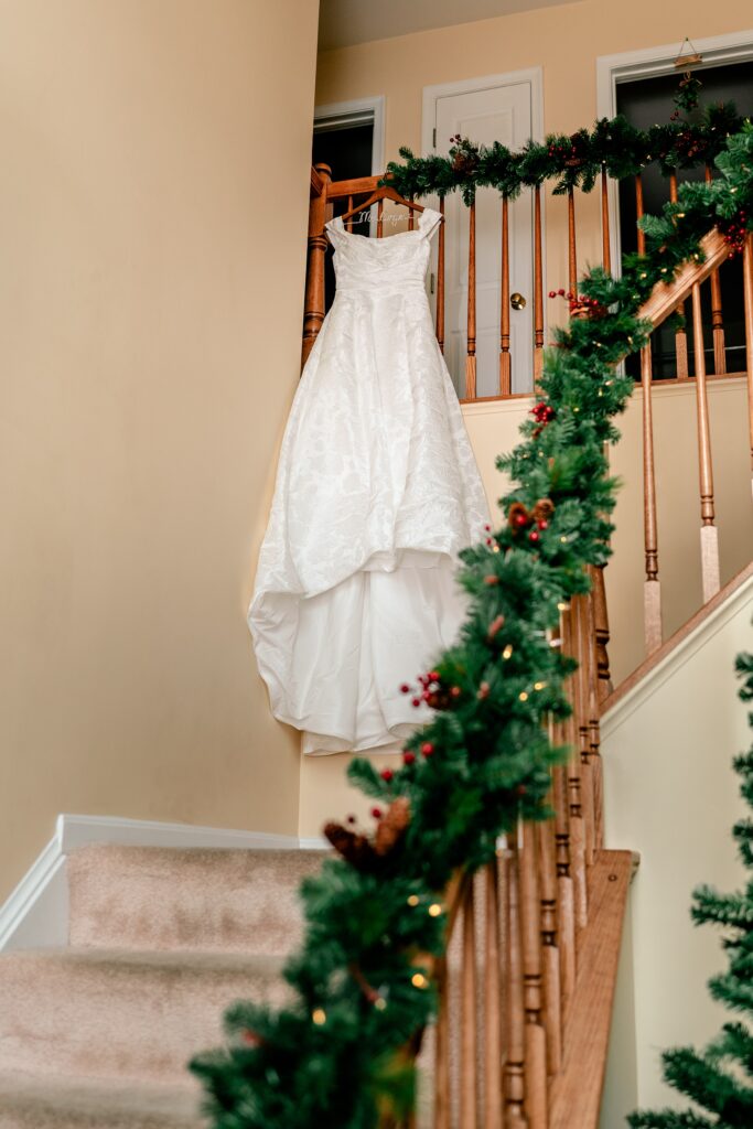A wedding dress hanging from the railing of a home decorated for a Christmas wedding