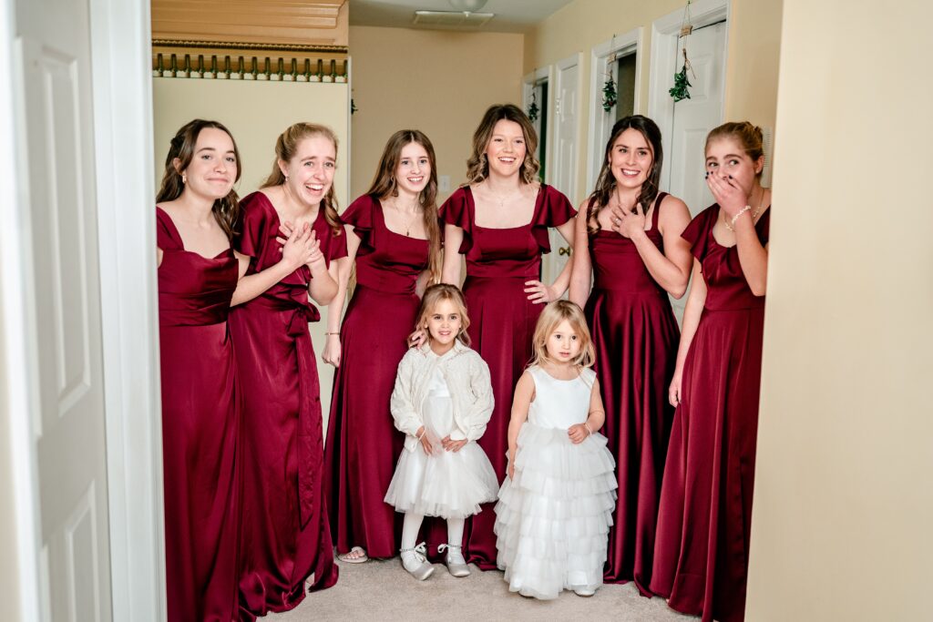 A bridesmaids first look with smiling bridesmaids in red dresses before a St Francis de Sales wedding in Purcellville