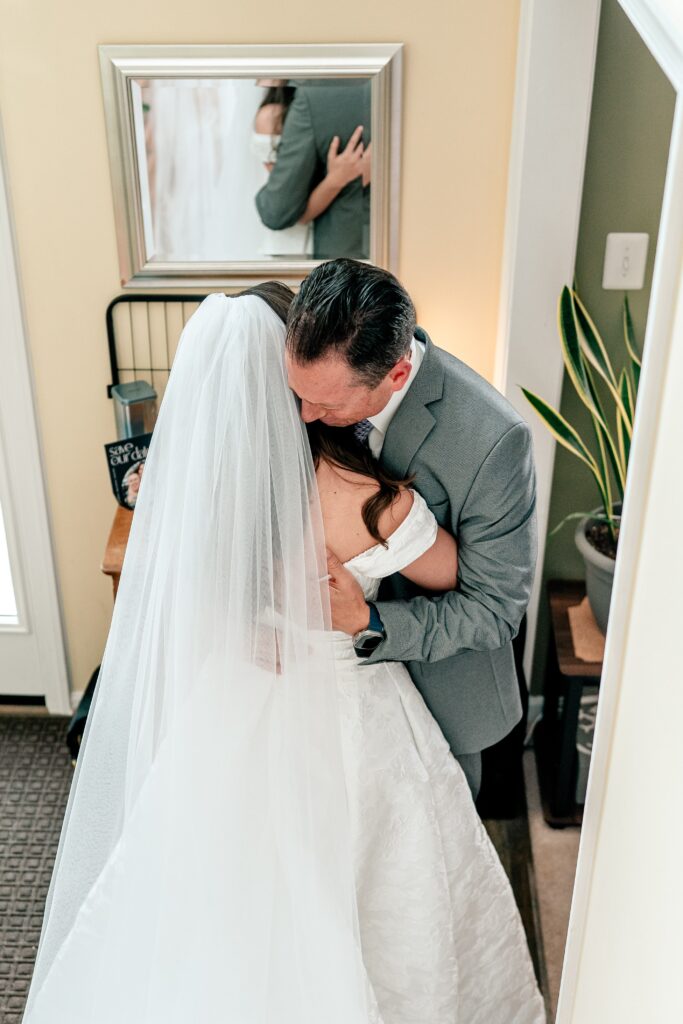 A father hugging the bride during their first look before a St Francis de Sales wedding in Purcellville