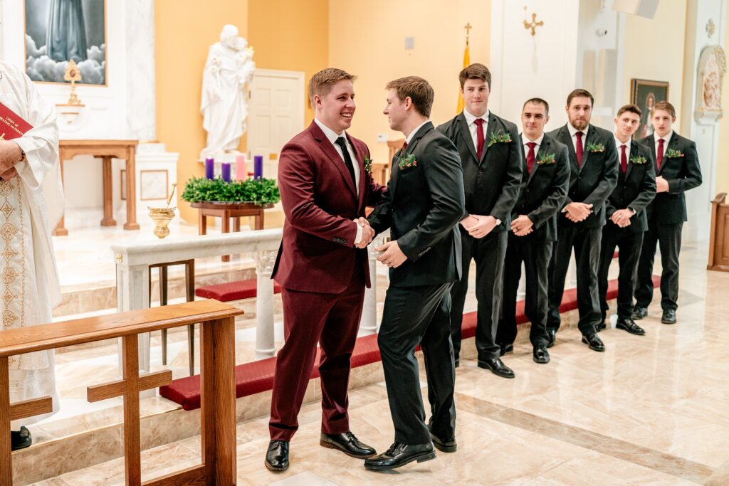 A groom greeting his best man at the start of his ceremony for a St Francis de Sales wedding in Purcellville