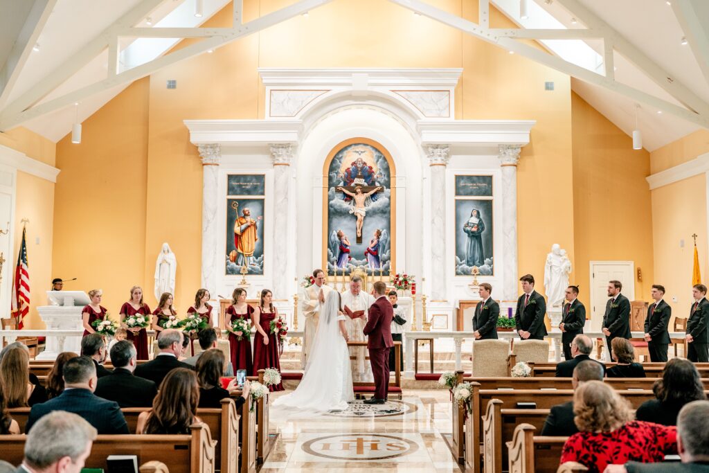 A bride and groom standing at the altar with their wedding party for their St Francis de Sales wedding in Purcellville