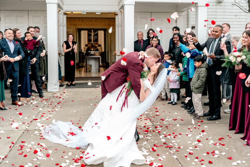 A romantic kiss during a flower petal sendoff from a St Francis de Sales wedding in Purcellville
