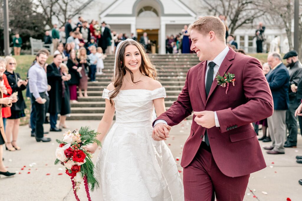 A bride and groom smiling as they end their flower petal sendoff after a Catholic wedding in Purcellville