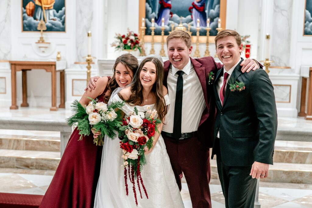 A wedding party posing happily for their portrait inside the church