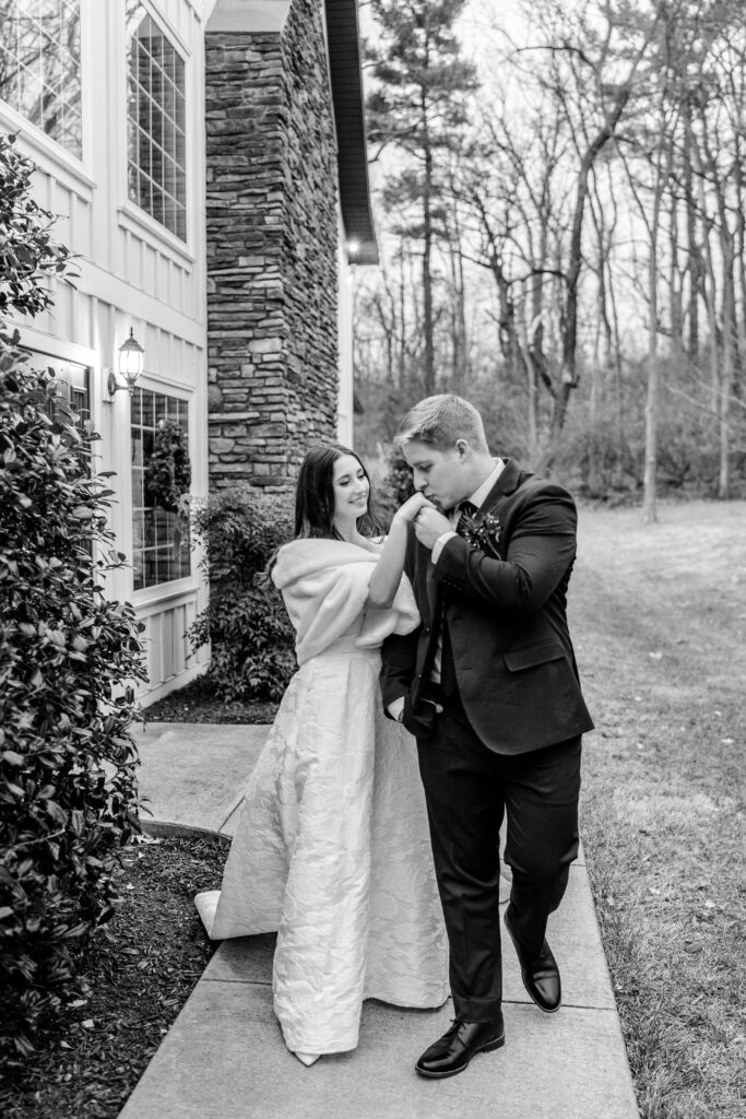 A groom kissing his bride on the hand as they walk together