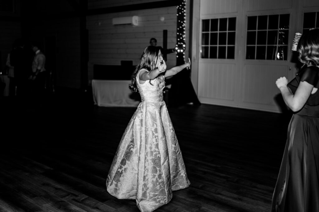 A bride posing on the dance floor for the start of her barn wedding reception