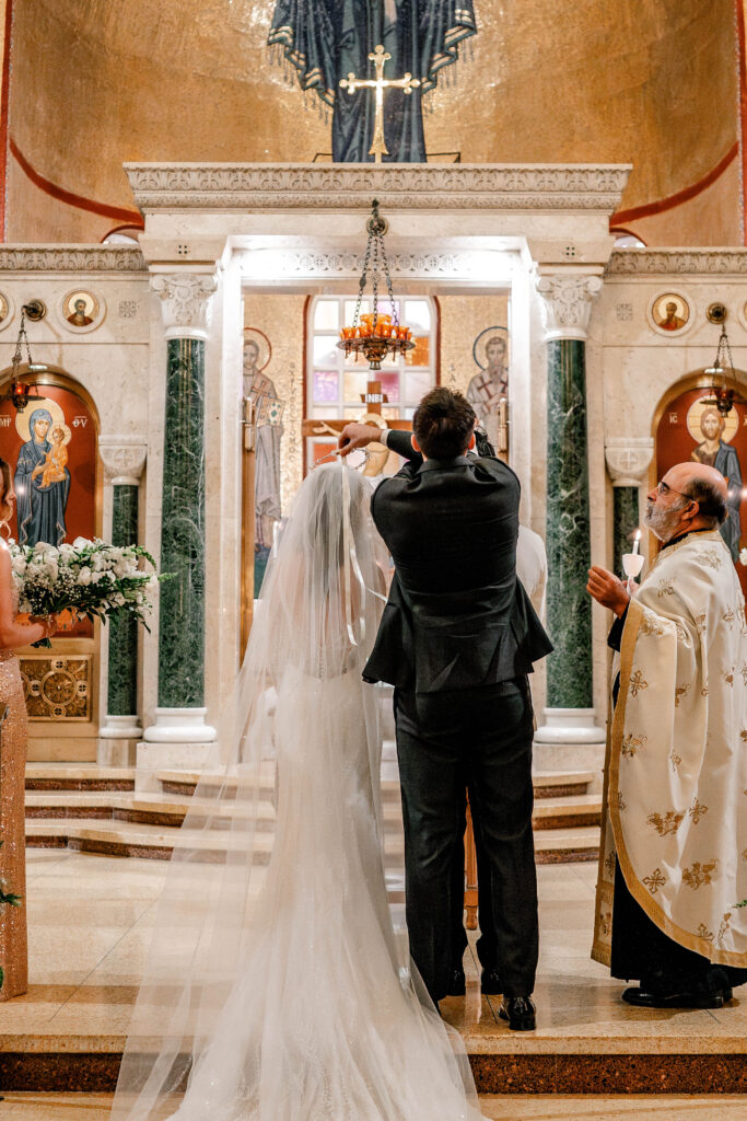 The best man placing crowns on the bride and groom