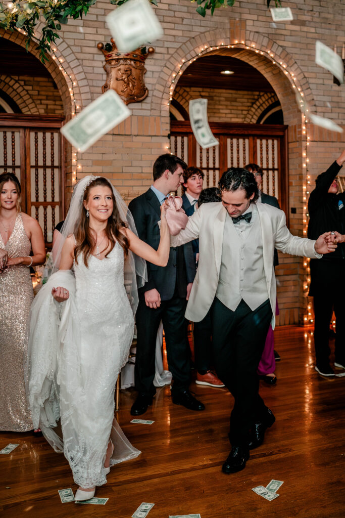 A bride and groom dancing as cash falls from the ceiling during their money dance