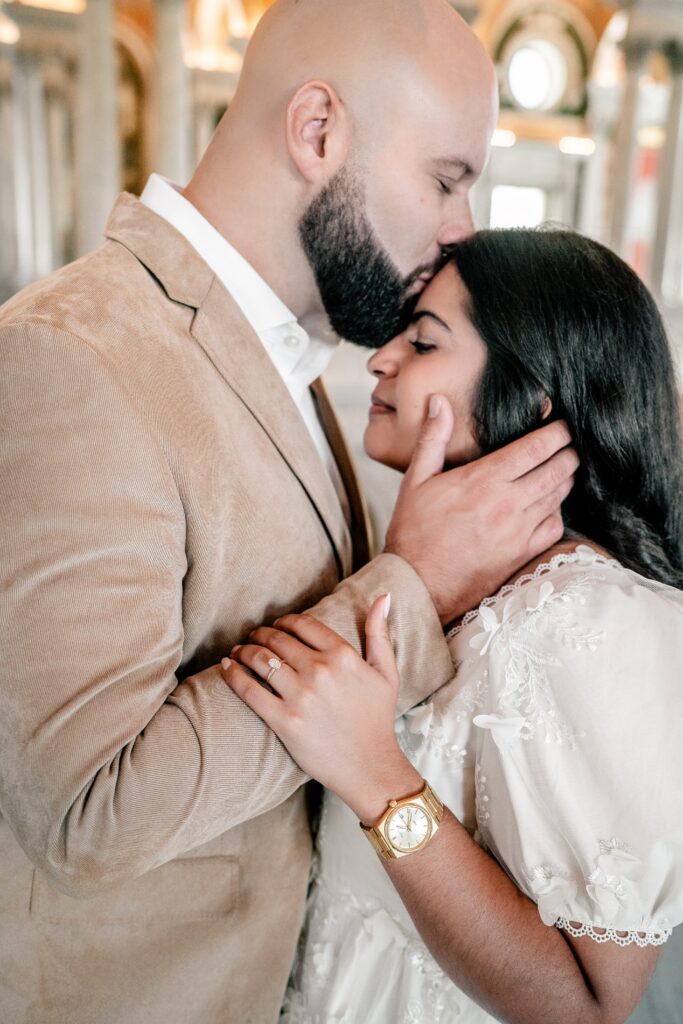 A man kissing the forehead of his future wife during their Washington DC engagement photos