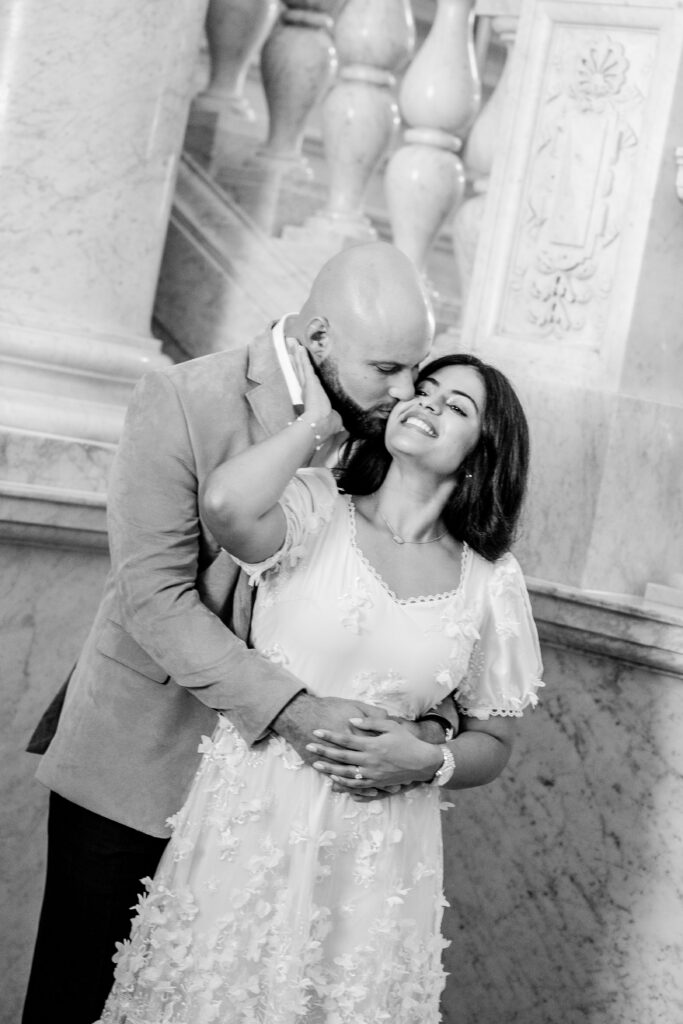 A man kissing his woman on the cheek with his hands around her waist
