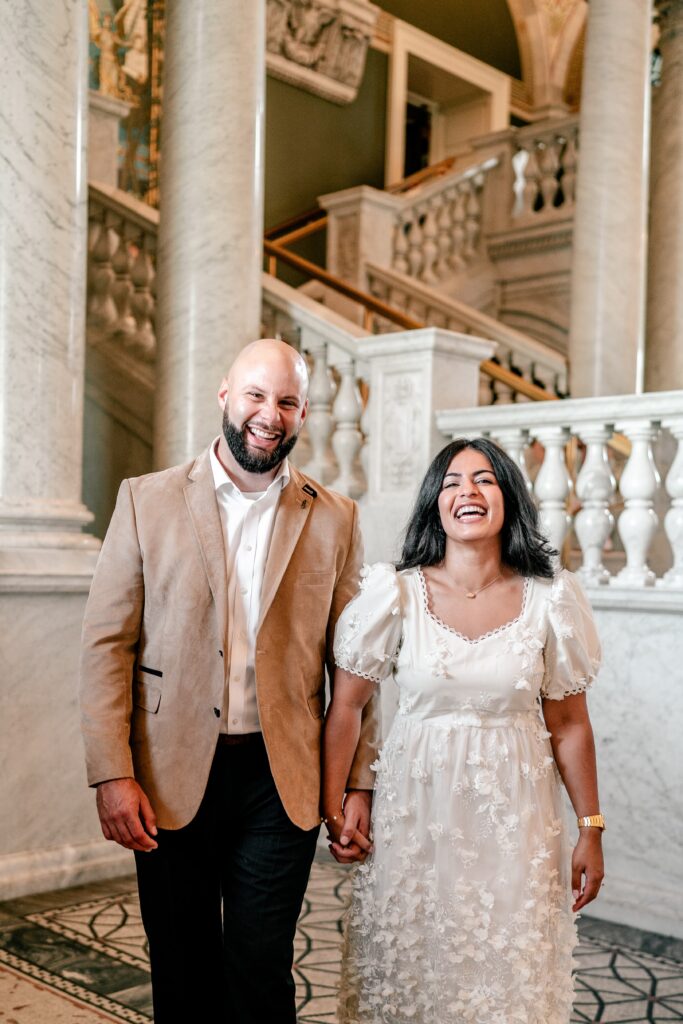 A couple laughing at the camera as they hold hands during their Washington DC engagement photos