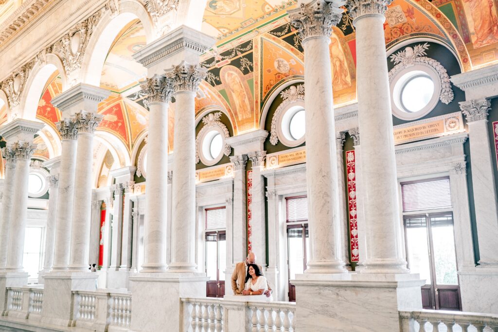 A wide shot of a man and woman leaning against a marble railing