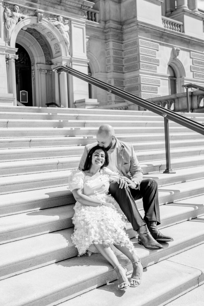 A man and woman sitting on an outdoor marble staircase