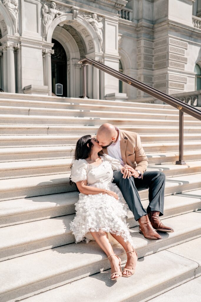 A couple shares a kiss on the front steps for their Library of Congress engagement photos