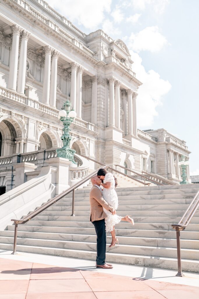 A dramatic lift kiss in front of the Library of Congress at midday
