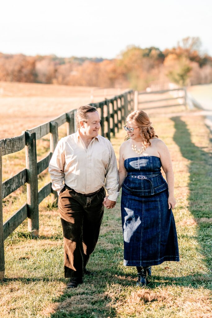 A couple walking together along a fence during their fall engagement photos near DC