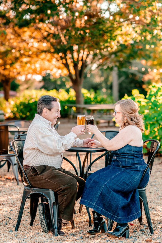 A couple toasting their beers together for their Maryland engagement photos