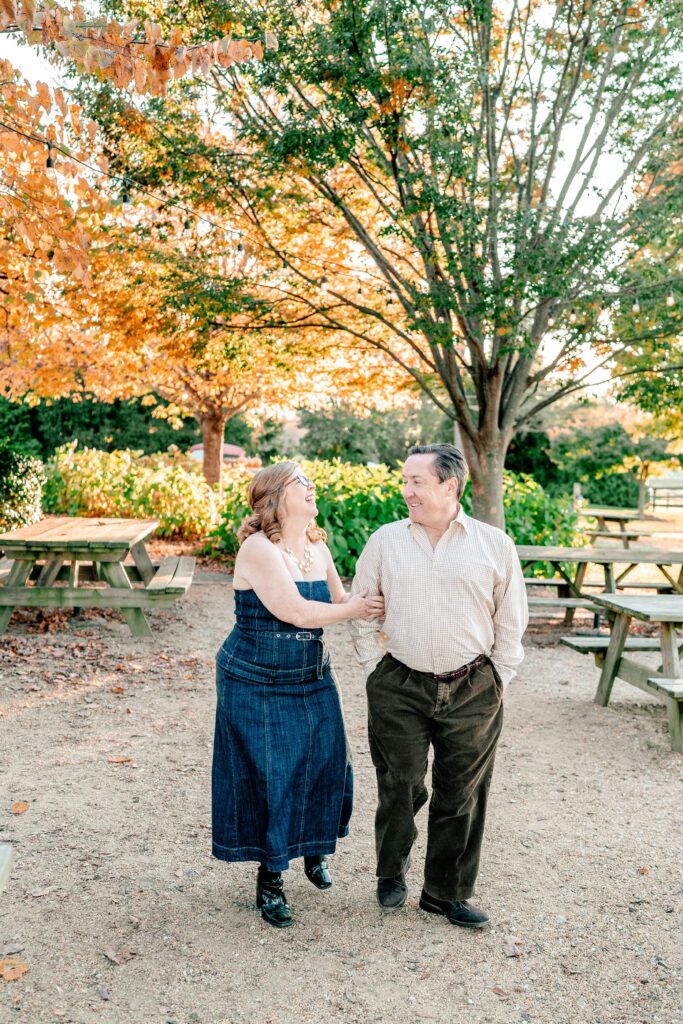 A couple laughing and walking together across a patio for brewery engagement photos
