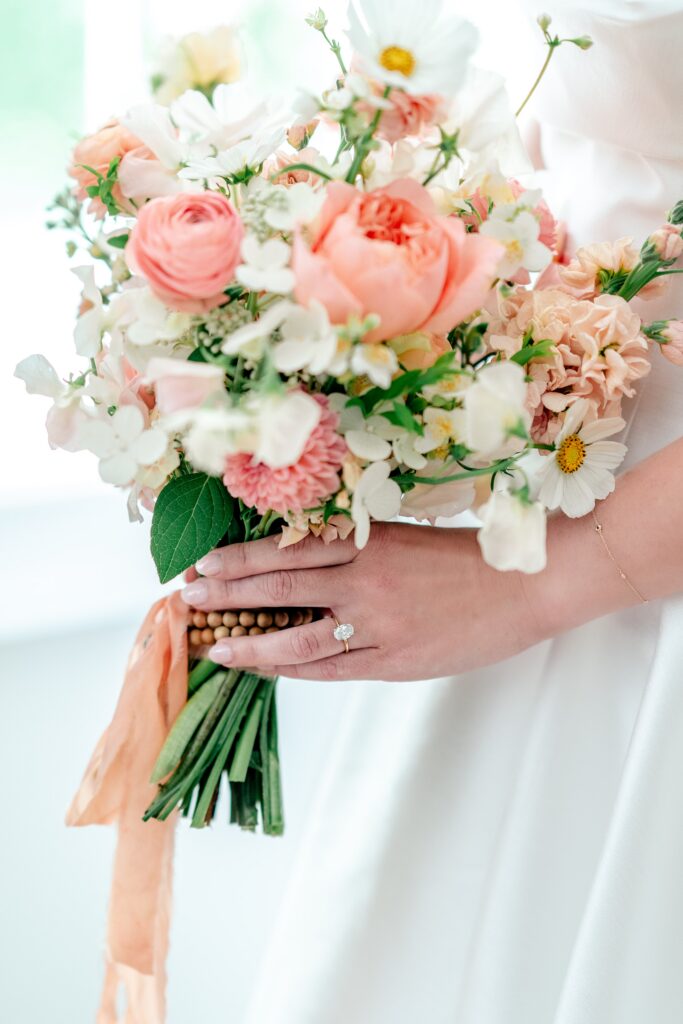 A bride's engagement ring on her finger as she holds her bouquet