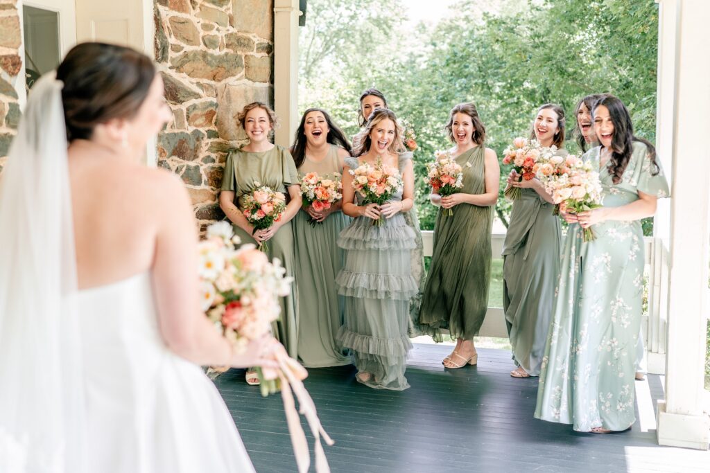 Bridesmaids cheering for the bride during their first look on the porch