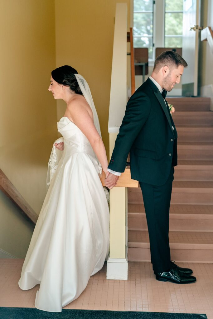 A bride and groom holding hands back to back for a Shadow Creek wedding first touch