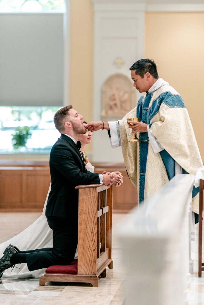 A groom receiving communion before his Shadow Creek wedding reception