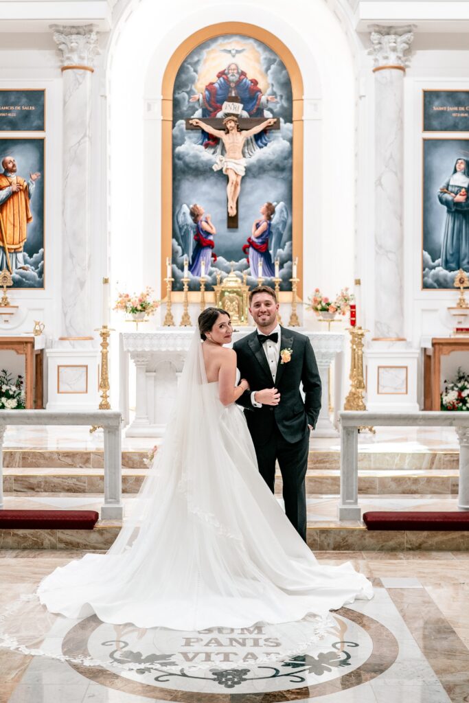 A bride and groom standing in front of the altar for their portraits