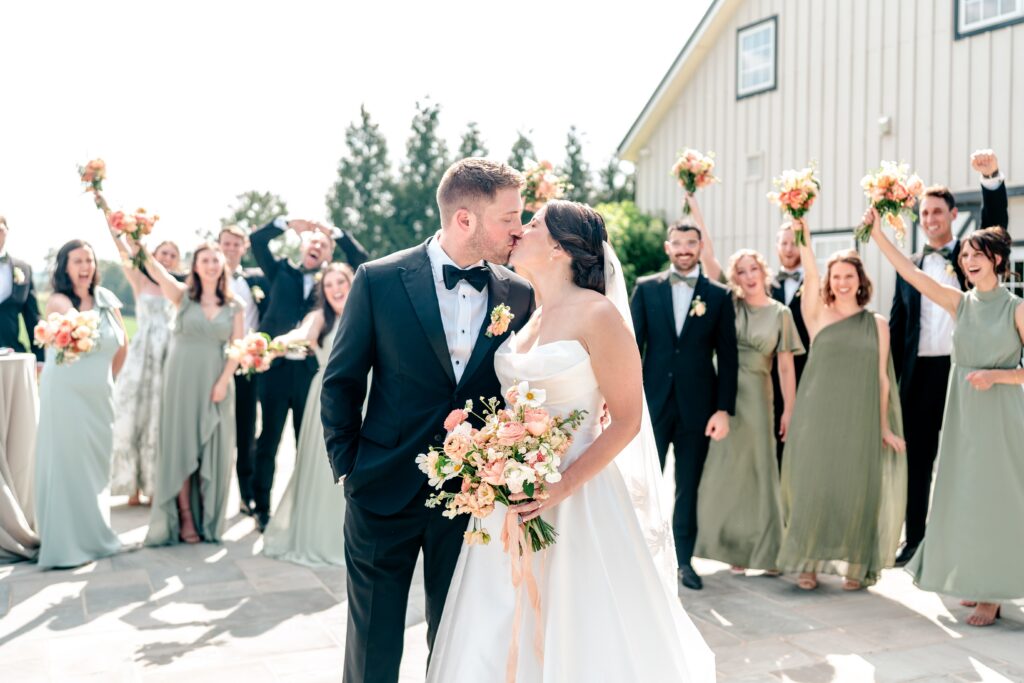 A wedding party cheers as the bride and groom kiss during their Shadow Creek wedding