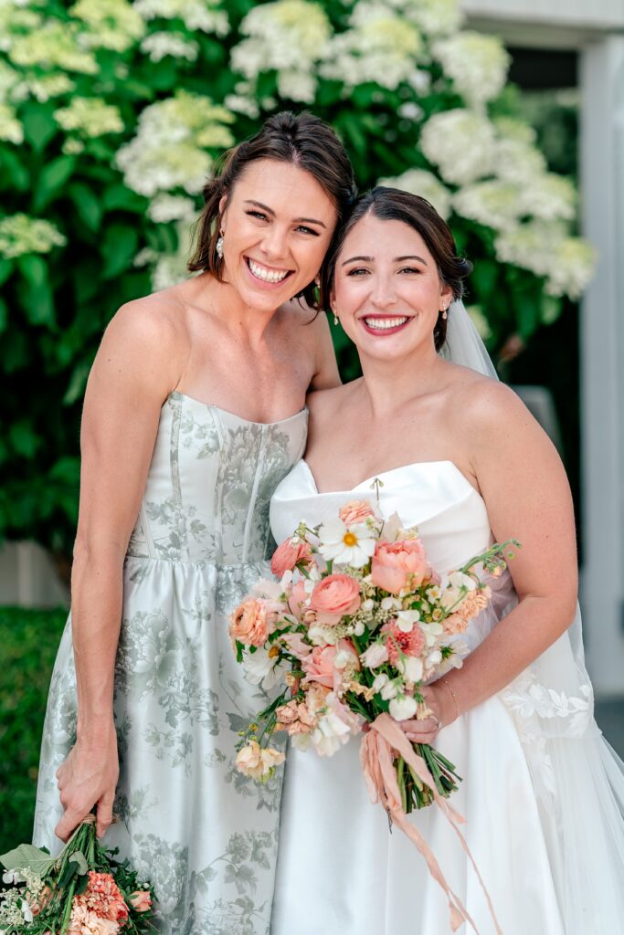 A bride and her maid of honor smiling for a classic portrait