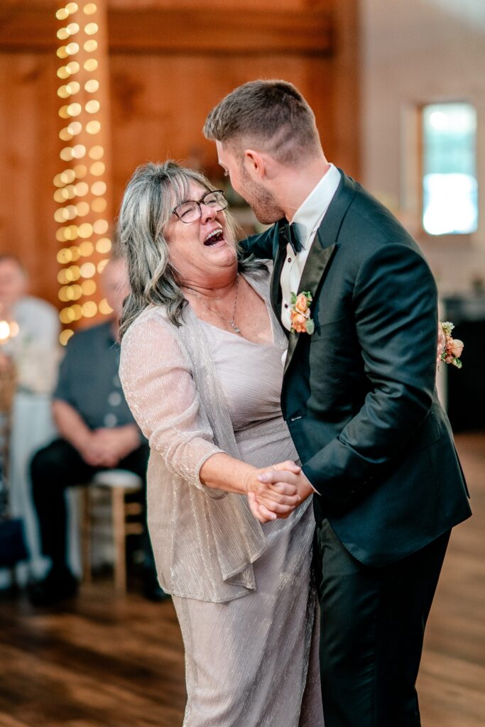 A groom and his mother dance together and she laughs with teary eyes during a Shadow Creek wedding reception
