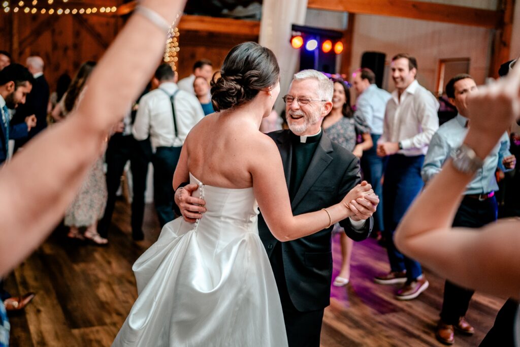 A bride dancing with the priest at her wedding reception